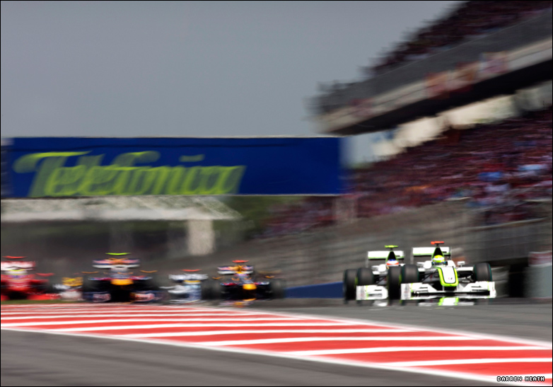 Two Brawn cars blasting away from the field