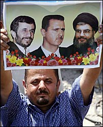 تظاهرکننده لبنانی با تصوير بشار اسد، محمود احمدی نژاد و حسن نصرالله