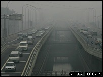 Vehicles drive on a street which is shrouded with smog on July 8, 2008 in Beijing.