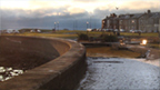 Colour view of pedestrian area of paving and grass at Troon Esplanade in the early evening light of a snowy day.