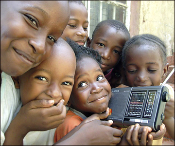 Sierra Leone: A young Sierra Leonean girl holds on tightly to her radio as her friends crowd round to enjoy another broadcast from the BBC.