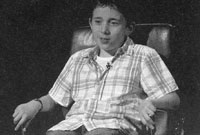 Rhys Muzzupappa yn eistedd yng nghadair Mastermind