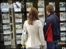 Couple looking at flat adverts in a window