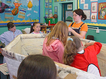 Plant yn gweithio ar gwch wedi'i wneud o gardbord.