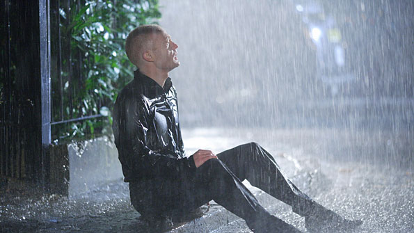 Man slumped in heavy rain.