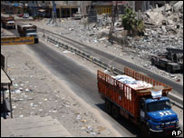 Caminhões de comboio da ONU passam por prédio destruído no caminho entre Sidon e Tiro