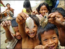 Những đứa trẻ giơ cho du khách xem một con cá ở Biển Hồ