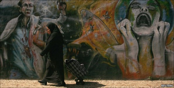 A woman wheels a trolley past a design of a screaming woman in Lisbon, Portugal