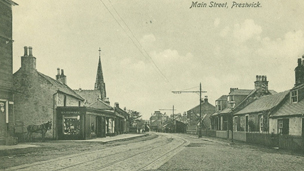 Black and white view of Main Street, Prestwick, showing tram-lines and a double-decker tram in the distance.