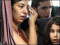 يک زن لبنانی که همراه اعضای خانواده اش شهر صور را ترک می کند، اشک آلود است