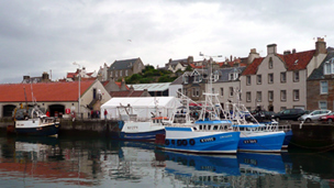 View across Pittenweem habrour to moored boats and the covered fish market.