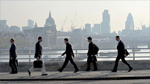 People walk across Waterloo Bridge with the City in the background