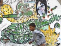 ایک پوسٹر کے قریب سے گزرتا ہوا فلسطینی لڑکا