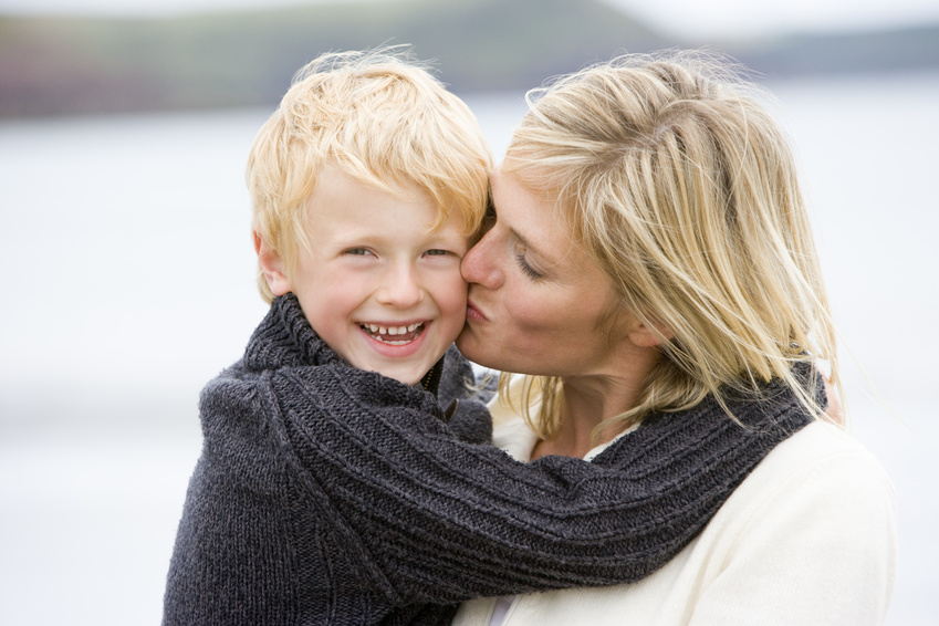 Mother kissing son at beach smiling @ monkey business - fotolia