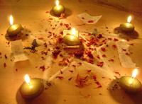 Five-pointed star, point upwards, constructed of sand and rose petals with a candle in the middle