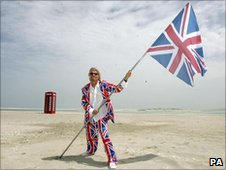 Richard Branson holding a Union Jack flag on Island of Britain - part of the man-made map of the World off the coast of Dubai