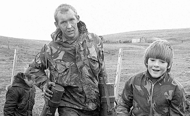 A boy helps a British soldier carry equipment. (Photo: Getty Images)