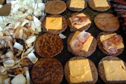 Burgers and onions frying on a hot plate.
