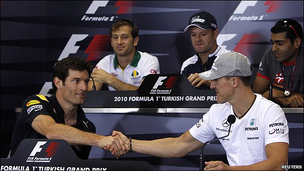 Mark Webber and Michael Schumacher shake hands during a news conference with Jarno Trulli, Rubens Barrichello and Karun Chandhok behind