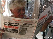 Mulher lê jornal em Havana