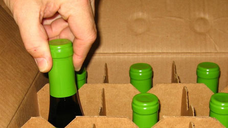 Rhiwyn yn cymeryd potel o win o focs.