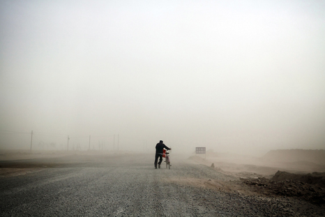 A man pushes his bike into an enveloping sandstorm on the outskirts of the town of Hongsibao, in Ningxia Province. 2009