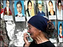 Mulher observa retratos de crianças mortas durante massacre em escola de Beslan