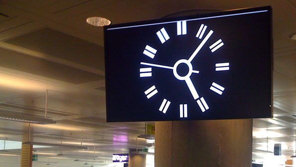 1980s style BBC2 clock, on a widescreen monitor, high on a pillar, in an open plan office