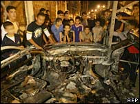 Palestinos ao redor de carro destruído na Faixa de Gaza