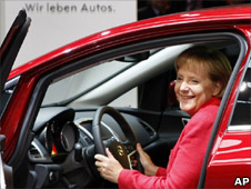 German Chancellor Angela Merkel sits in an Opel Astra car at the IAA Frankfurt Auto Show in Frankfurt, Germany, 17 Sept 2009. Slogan translates 'We live cars'
