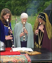 Three women in medieval costume playing recorders
