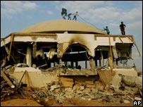 Palestinos no teto de sinagoga incendiada no antigo assentamento de Netzarim, em Gaza