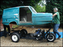 A man putting a Robin Reliant car together