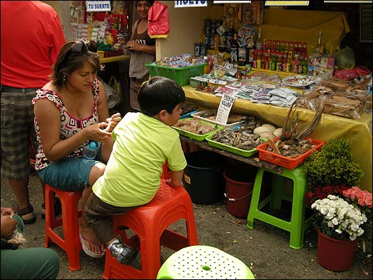 Una señora con un niño frente a un puesto de venta