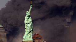 Statue of Liberty in front of smoking buildings