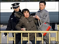 Pekin'de bir gösterici polis tarafından götürülüyor