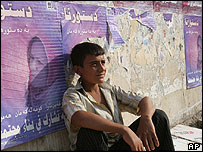 Vendedor ambulante em Bagdá descansa em frente a cartazes sobre referendo constitucional