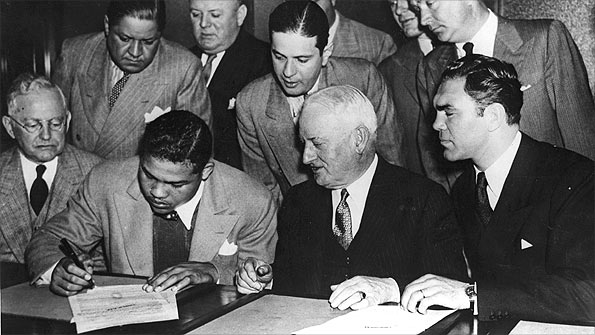 Joe Louis (left) signs as Max Schmeling looks on