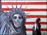 دختری در حال عبور از جلوی نقاشی ديواری ضد آمريکايی در تهران