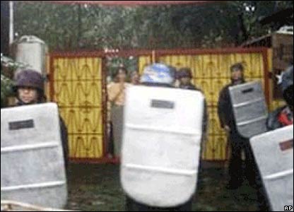 Police guard Aung San Suu Kyi (left in background).