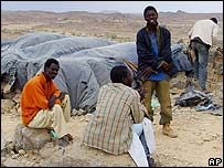 Liberian migrants sit next to their shelters outside a town in southern Algeria