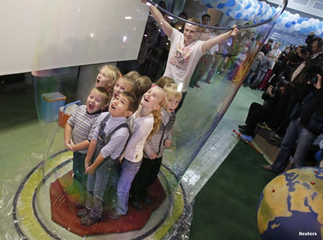 A giant bubble is formed around a group of children.