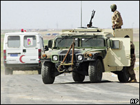 Ambulância se dirige para o local da explosão em Mosul, passando por soldados iraquianos