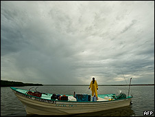 Un pescador se apresta a sacar su bote del agua ante la llegada del huracán