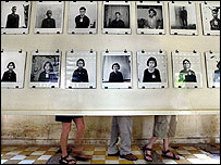 Kızıl Kmerlerin kurbanlarının fotoğrafları ve fotografların arkasında duran turistler