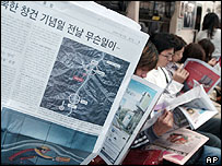 Jihokorejští cestující si čtou o výbuchu v Severní Koreji