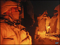 یک تفنگدار دریایی آمریکا، در کنار دو مظنون بازداشت شده، در ولسوالی گرمسیر