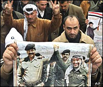 پوستر صدام حسين و ياسر عرفات در دست مرد فلسطينی