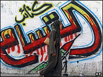 زنی در غزه از برابر نام گرافيکی گروه قسام می گذرد