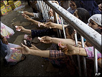 Mulheres paquistanesas tentam receber alimentos